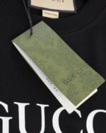 Gucci（グッチ） コピー 芸能人 ベルトロゴダブルgテーププリントラウンドネック半袖Tシャツ